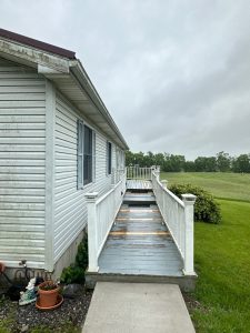 deck cleaning on a residential home with visible dirt and algae on the surface and cloudy sky in the background